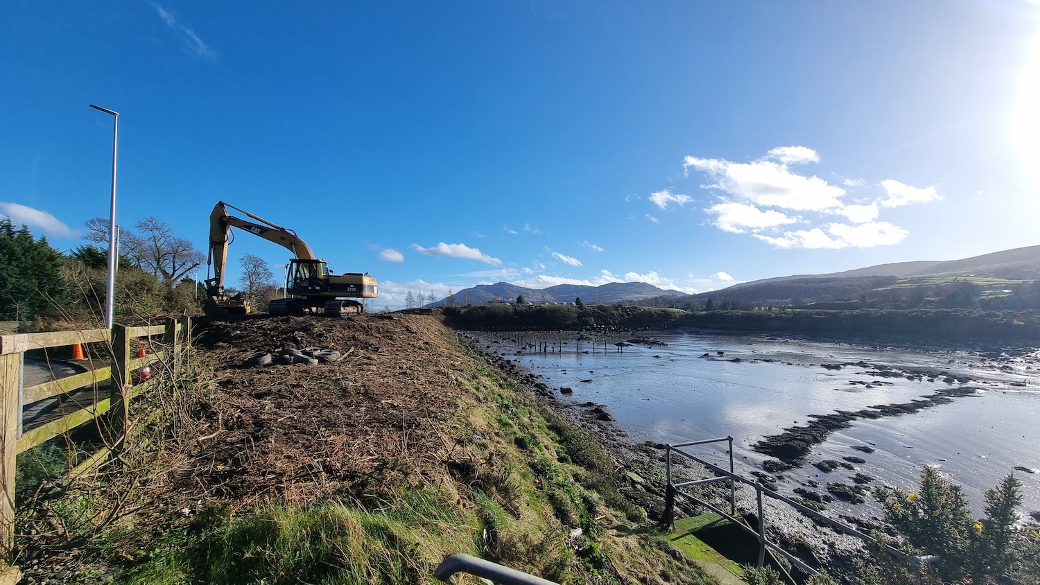 Water on the right, then a coastline in
                          the centre and on the left is a grassy verge
                          with a digger moving earth around.