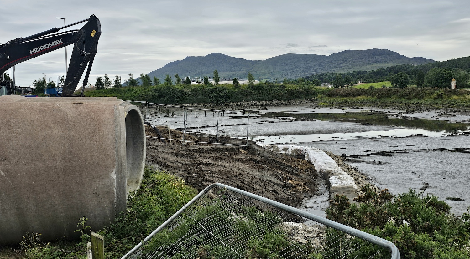 View along the side of a river with
                          recent earthworks extending into the river and
                          large concrete pipes on the left.