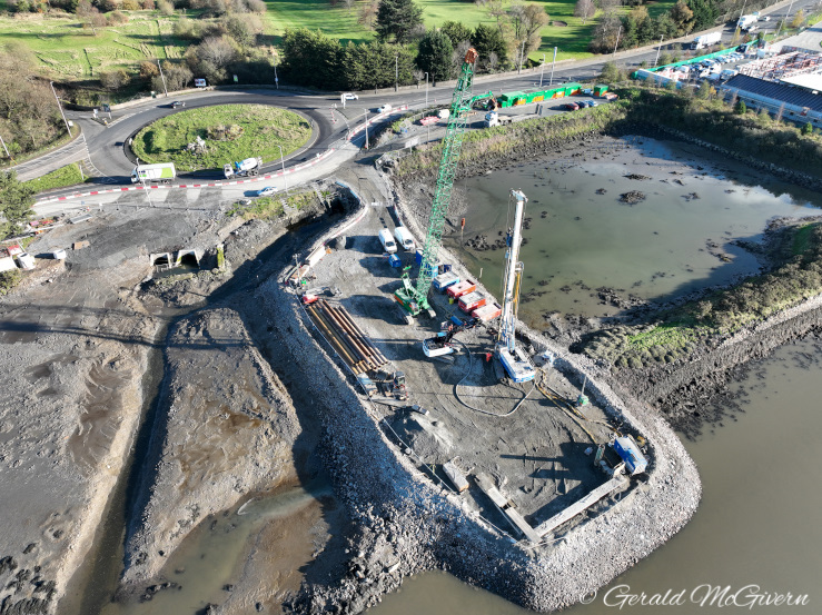 Rock platform partially in water with a
                          pile driver at the end of it.