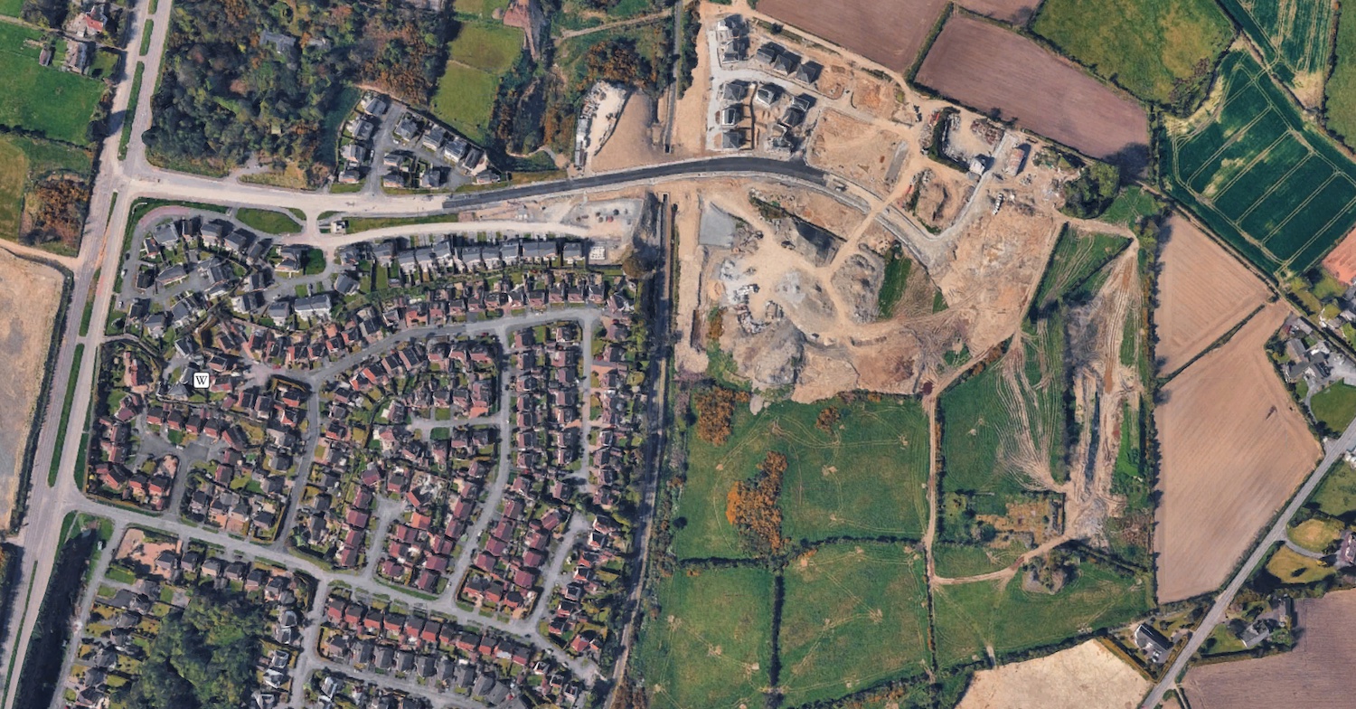 Aerial view showing a road and homes
                          under construction towards the right and
                          completed to the left.
