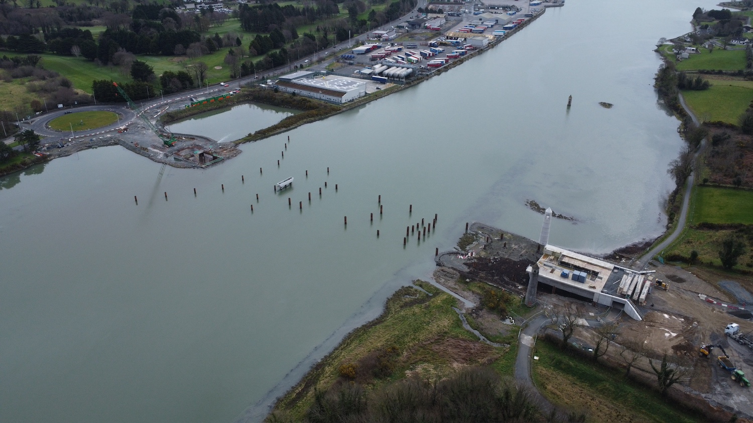 Aerial view with river from bottom left
                          to top right. Lots of vertical piles evident
                          in a line between the two abutments which are
                          under construction.
